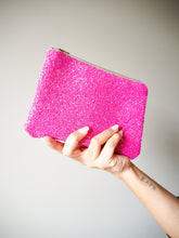 This sparkly hot pink makeup bag has gold hardware on the beige zip and a cotton lining with a floral print.