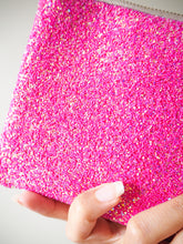This handmade hot pink glitter pouch has a shimmer of blue, purple, and gold rainbow glitter when it catches the light.