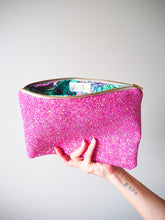 The lining of this sparkly hot pink clutch bag has a floral and paisley print in pink and green to match the exterior colour.