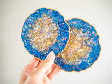 This Indigo Geode Heatproof Resin Coasters Set has a metallic shimmer of gold, iridescent flakes, and a shimmering purple.