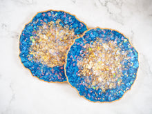 This Set of Handmade Suki Sabur Designs Indigo Geode Heatproof Resin Coasters has a sparkly gold centre and a metallic gold painted edge.