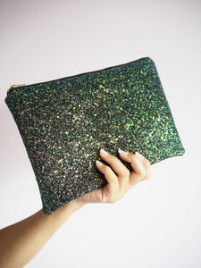 This sparkly black clutch bag has a shimmer of green, copper, gold, and blue glitter. You'll find a floral print cotton lining to complement the colour.